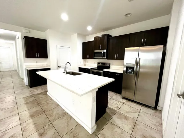 a kitchen with stainless steel appliances a refrigerator a sink a stove top oven and cabinets