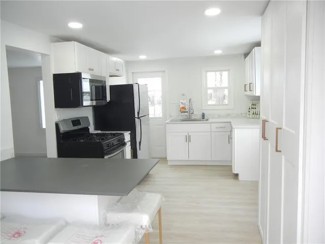 a large white kitchen with a refrigerator a sink a stove a microwave a counter top and cabinets
