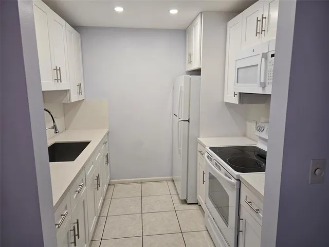 a kitchen with white cabinets and white appliances