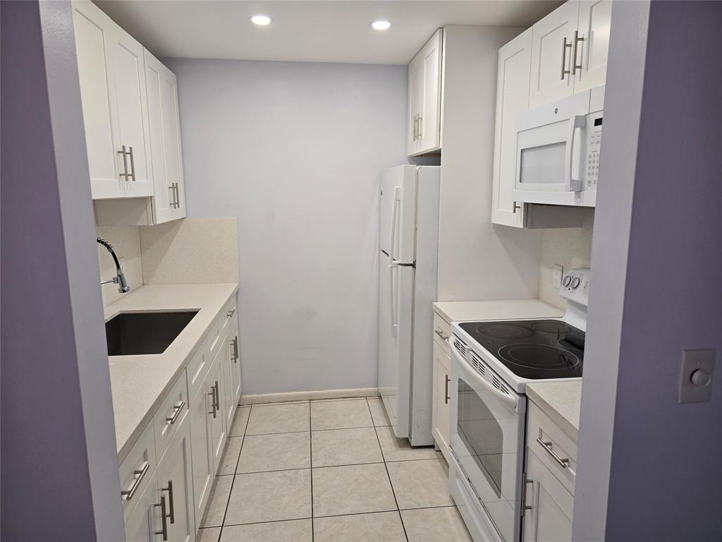 300 Southwest 134th Way, Unit E211 Pembroke Pines, FL 33027 - Photo 4 of 24 a kitchen with white cabinets and white appliances