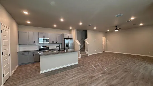 a kitchen with stainless steel appliances kitchen island granite countertop a stove top oven a sink and a refrigerator