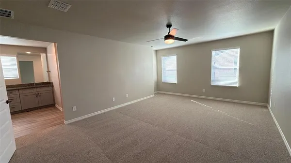 an empty room with windows and ceiling fan