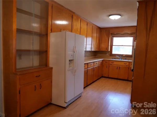 a kitchen with a refrigerator a sink and dishwasher with wooden floor