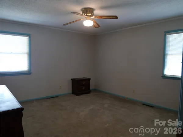 an empty room with windows and fan