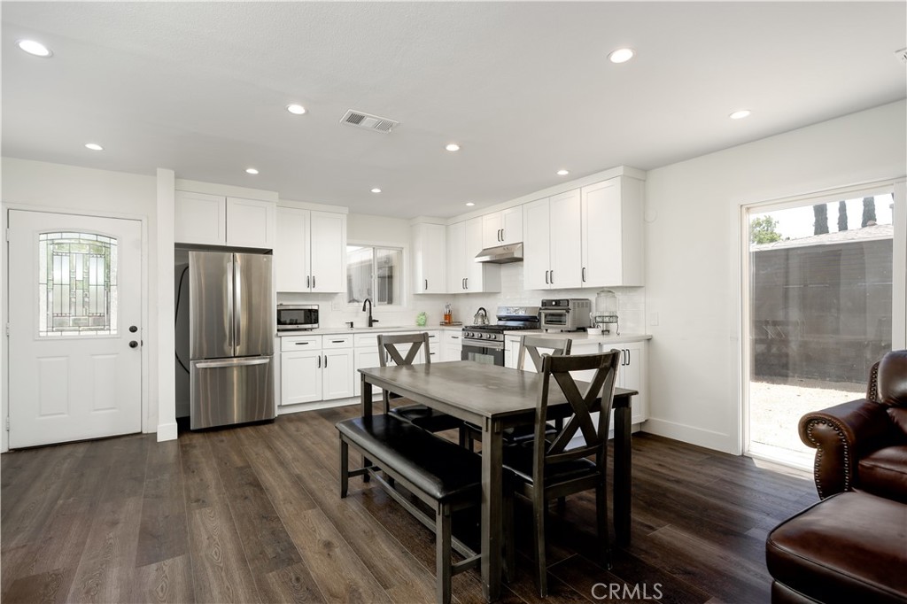 38859 Mesquite Road Palmdale, CA 93551 - Photo 5 of 36 a kitchen with stainless steel appliances a refrigerator a stove a sink a dining table and chairs with wooden floor