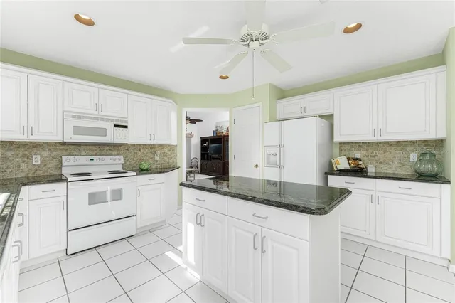 a kitchen with granite countertop white cabinets white stainless steel appliances with a sink and dishwasher