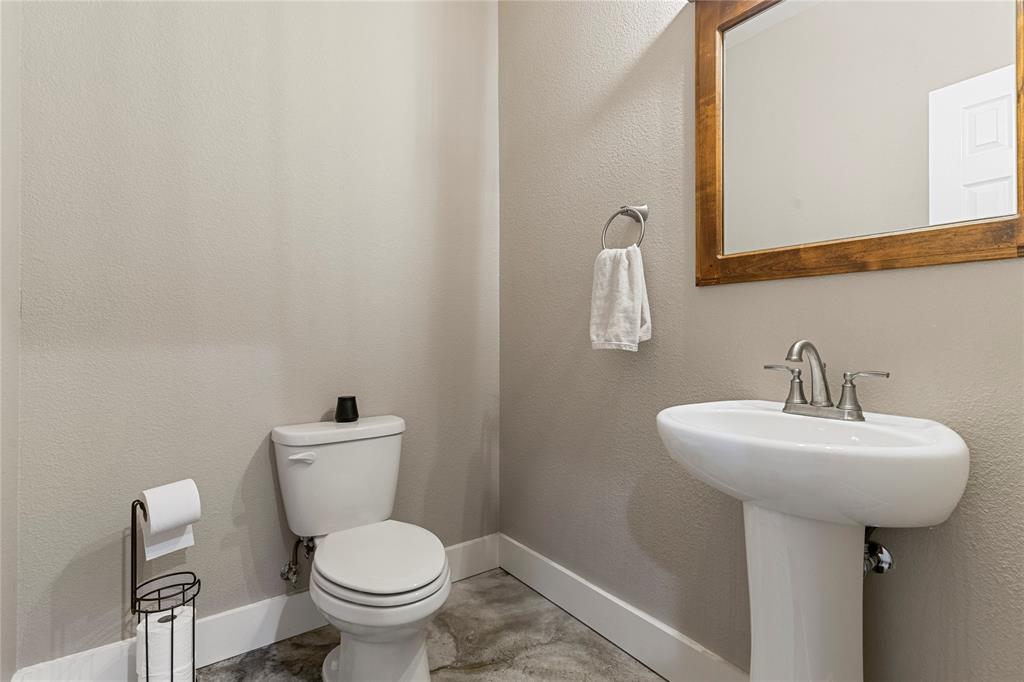 139 Kriston Lane Springtown, TX 76082 - Photo 17 of 39 Powder room featuring a pedestal sink with a brushed nickel faucet, a framed mirror, and a white toilet
