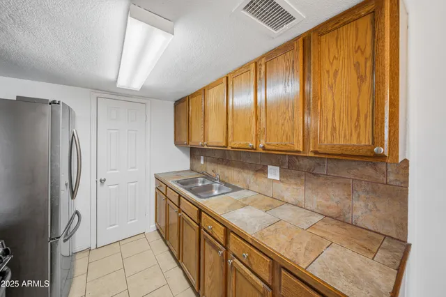 a view of a refrigerator in kitchen and an empty room