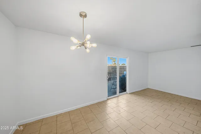 a view of an empty room with chandelier fan