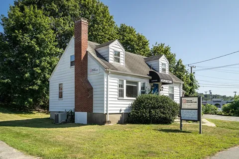 a view of a house with yard and trees in the background
