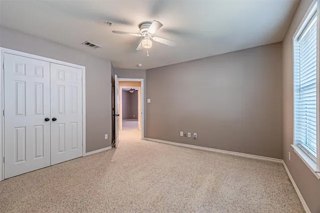 an empty room with chandelier fan and windows