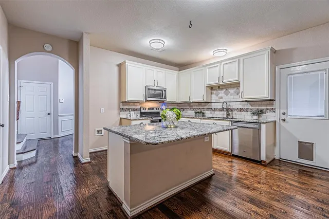a kitchen with granite countertop a sink cabinets stainless steel appliances and a counter space