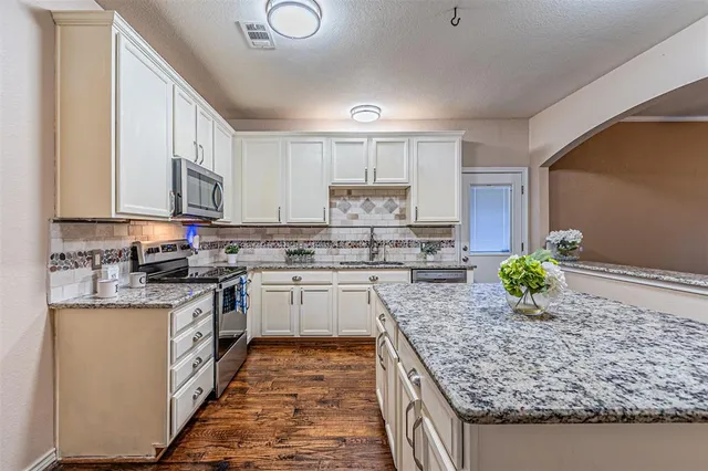 a kitchen with stainless steel appliances granite countertop a stove sink and cabinets