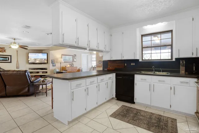 a kitchen with granite countertop a sink white cabinets and black appliances