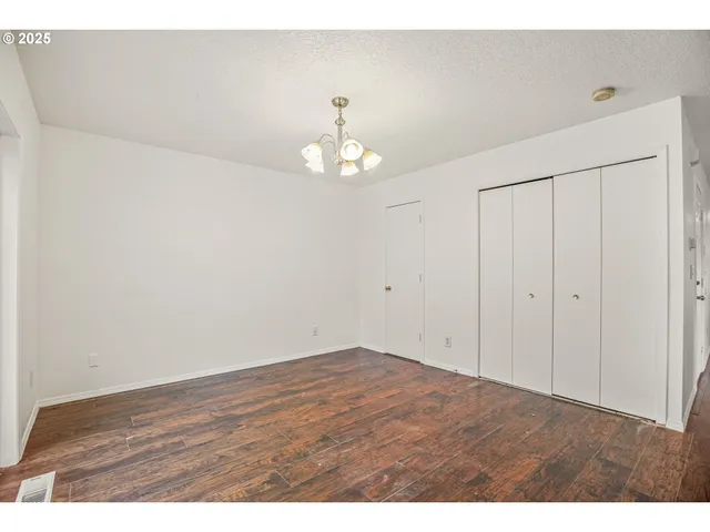 a view of an empty room with chandelier fan