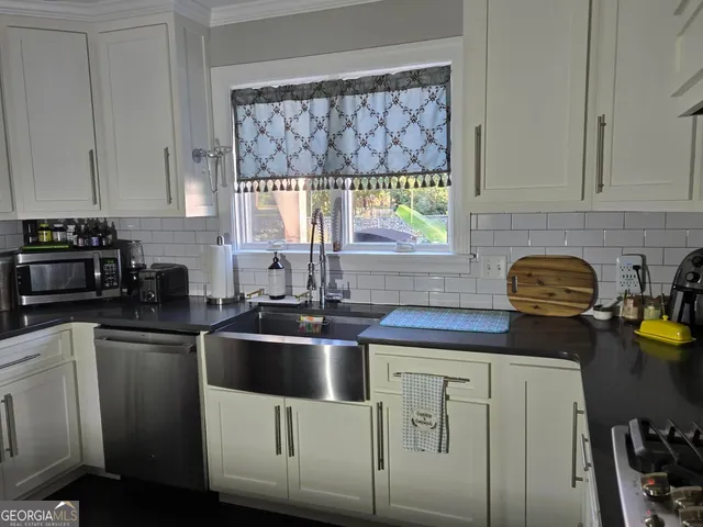 a kitchen with stainless steel appliances a sink a stove a window cabinets and a counter top space