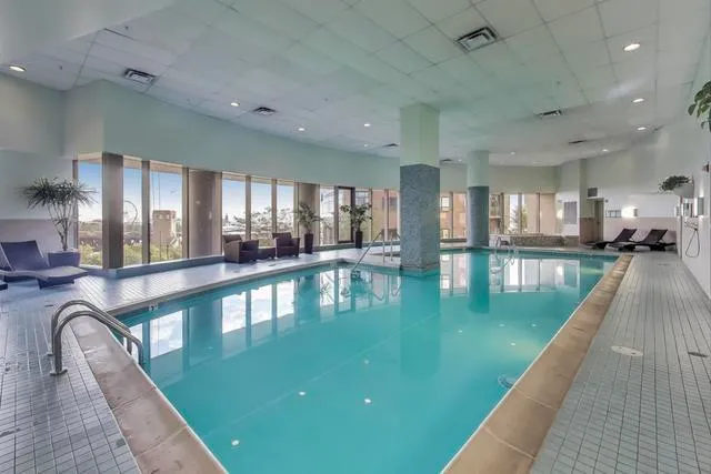 a dining hall with stainless steel appliances lots of white furniture wooden floor and a kitchen view