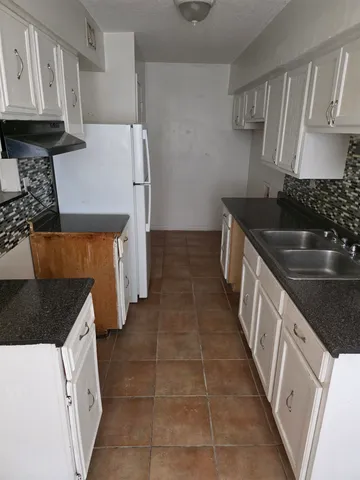 a kitchen with granite countertop a stove a sink and a refrigerator