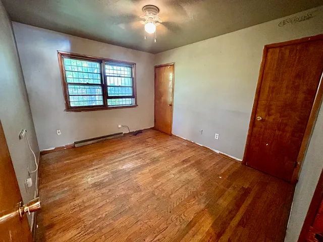 a view of an empty room with a window and wooden floor