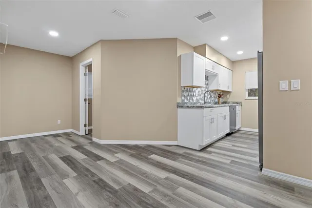 a view of kitchen with stainless steel appliances granite countertop cabinets and wooden floor