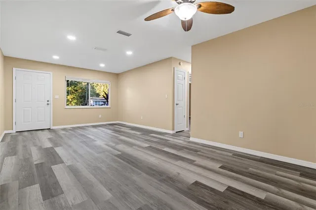 an empty room with windows and chandelier fan