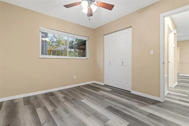 an empty room with wooden floor chandelier and windows