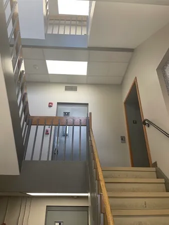 a view of staircase with lots of frames on wall and a window
