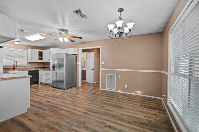 a view of a kitchen with a refrigerator a ceiling fan and wooden floor