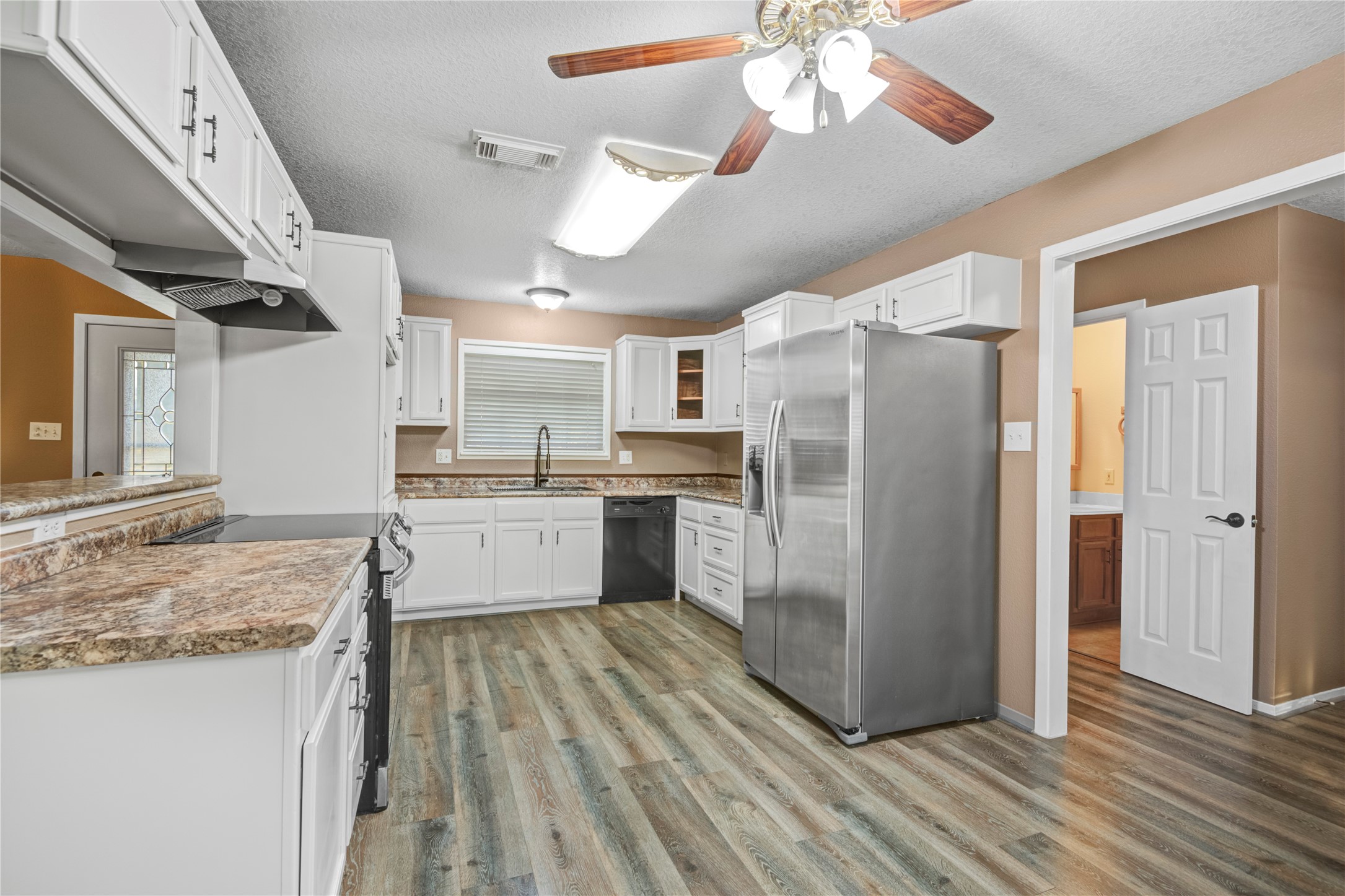 21503 Pecan Bend Road Damon, TX 77430 - Photo 14 of 39 a kitchen with stainless steel appliances granite countertop a refrigerator a sink dishwasher a stove and a dining table with wooden floor