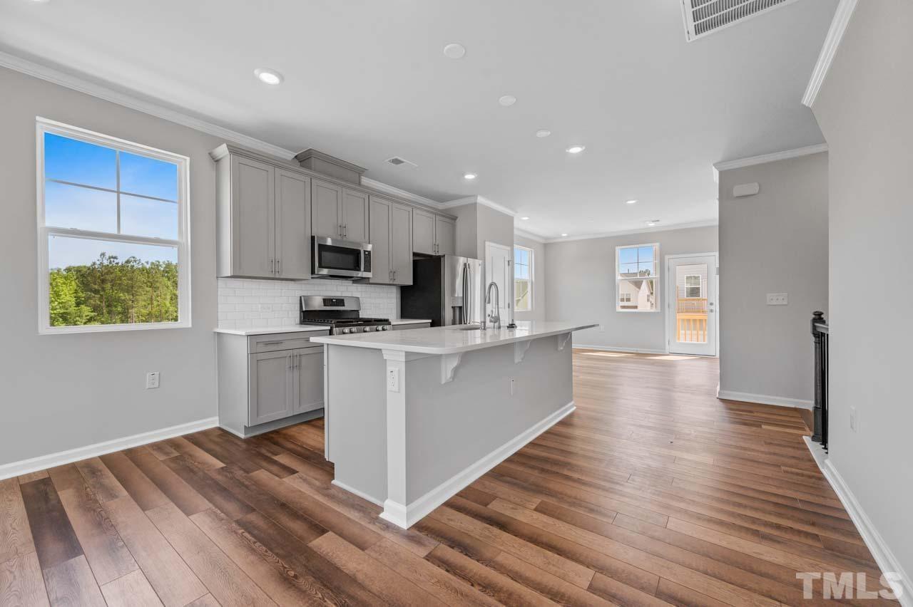 301 Devon Cliffs Drive Wake Forest, NC 27587 - Photo 4 of 26 a kitchen with stainless steel appliances granite countertop a refrigerator a stove top oven a sink and dishwasher with wooden floor