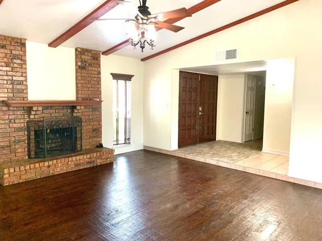 an empty room with wooden floor a fireplace and windows