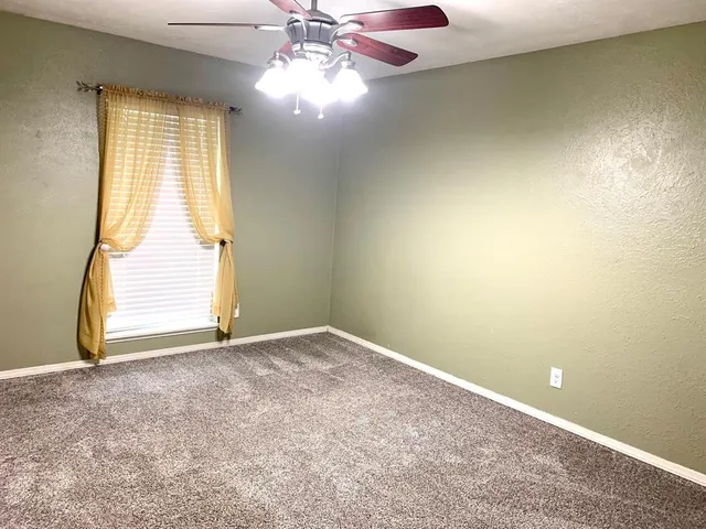 an empty room with windows and chandelier fan