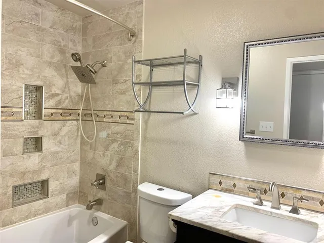 a bathroom with a granite countertop sink a toilet and shower