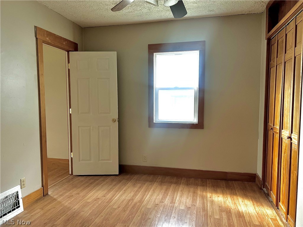 67 Forbes Road Bedford, OH 44146 - Photo 11 of 20 Unfurnished bedroom featuring a closet, light wood-type flooring, a textured ceiling, and a ceiling fan