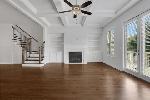 a view of an empty room with wooden floor fireplace and a window