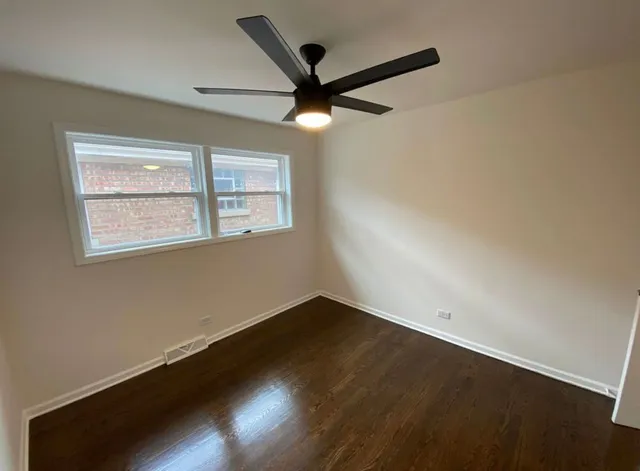 an empty room with wooden floor and fan