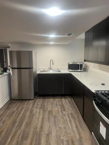 a kitchen with stainless steel appliances a sink cabinets and wooden floor