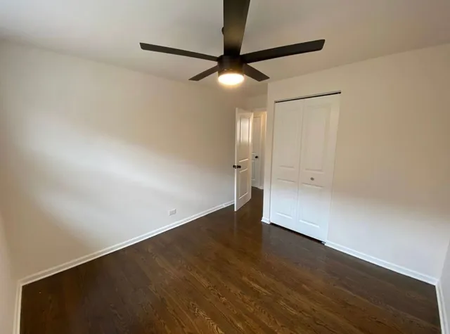 an empty room with wooden floor and a ceiling fan