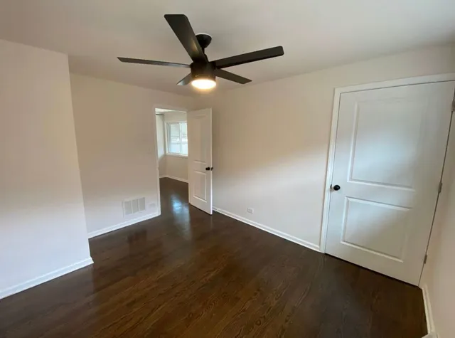 an empty room with wooden floor and a ceiling fan