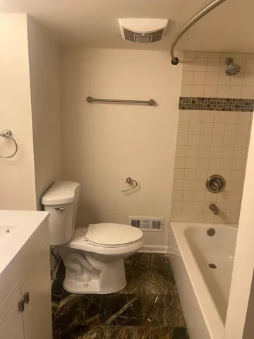 a white toilet sitting next to a bath tub