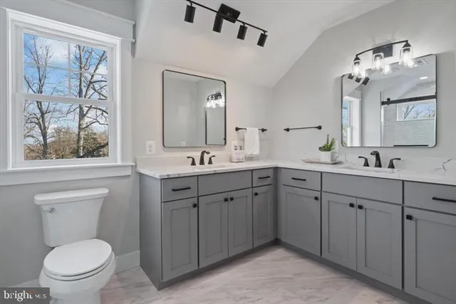 a spacious bathroom with a double vanity sink toilet and a mirror