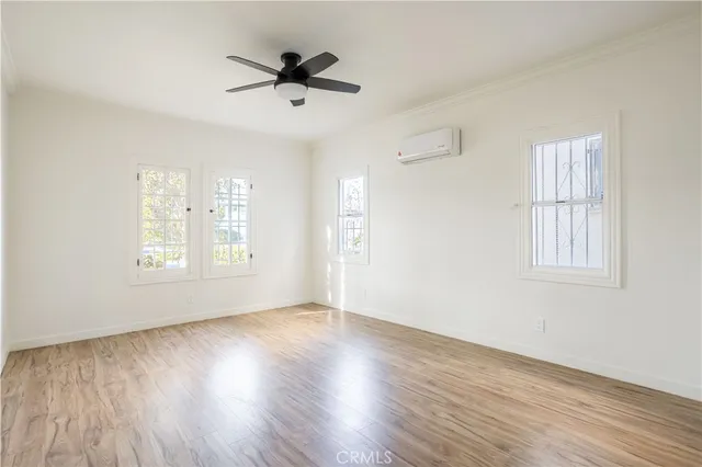 a view of empty room with wooden floor and fan