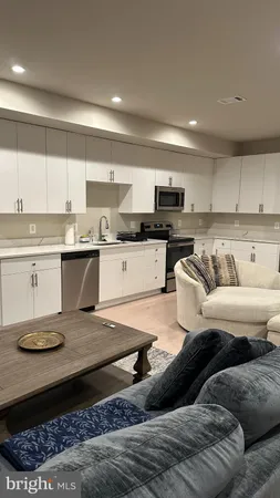 a living room with stainless steel appliances granite countertop a couch and cabinets