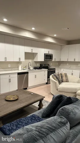 a living room with stainless steel appliances granite countertop a couch and cabinets