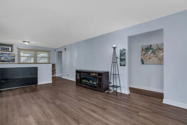 an empty room with wooden floor fireplace and window