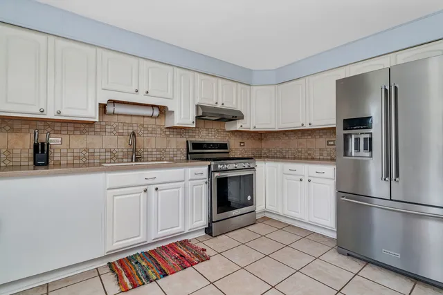 a kitchen with stainless steel appliances granite countertop a refrigerator and a stove top oven