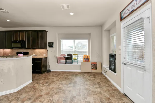 a large white kitchen with granite countertop a stove a sink a refrigerator and white cabinets with wooden floor