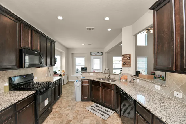 a large kitchen with granite countertop a sink stove and cabinets