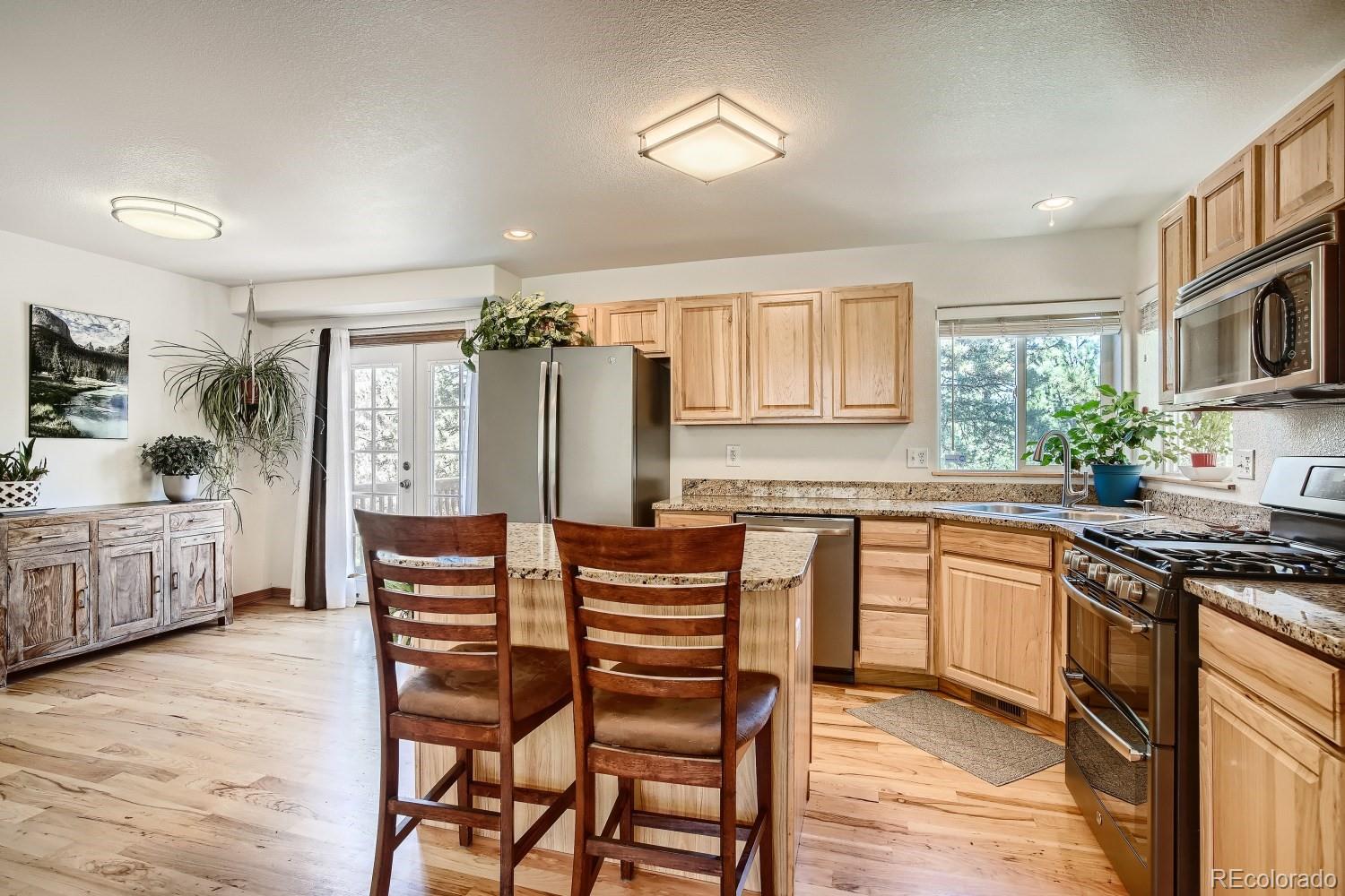 731 Hitchrack Road Bailey, CO 80421 - Photo 5 of 22 a kitchen with stainless steel appliances kitchen island granite countertop a table chairs sink and cabinets