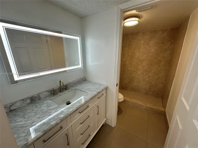a bathroom with a granite countertop sink toilet and shower